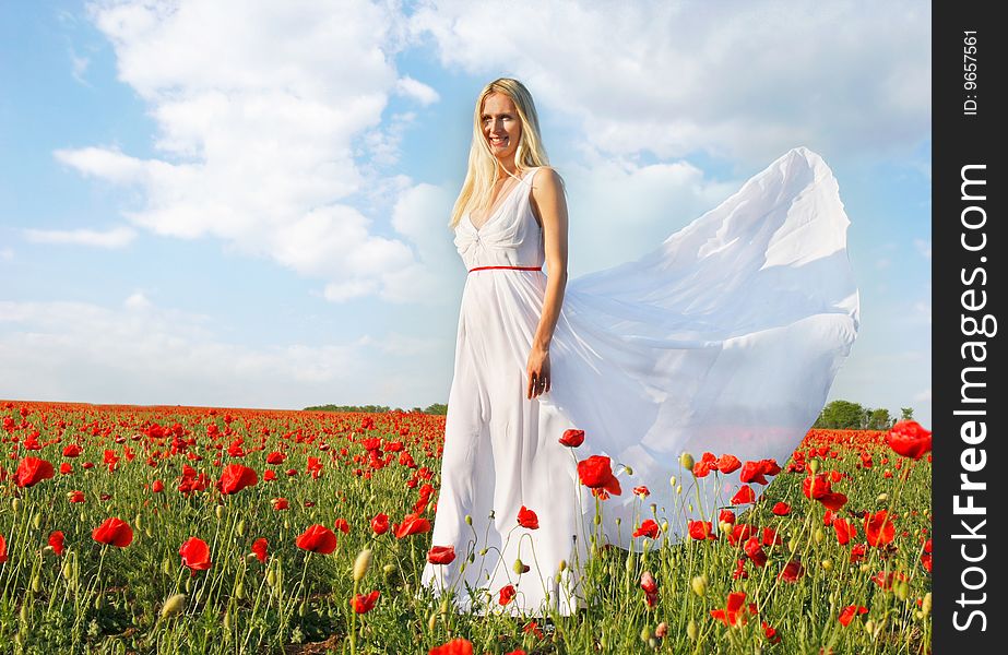 Young beautiful woman in white dress on poppy field background