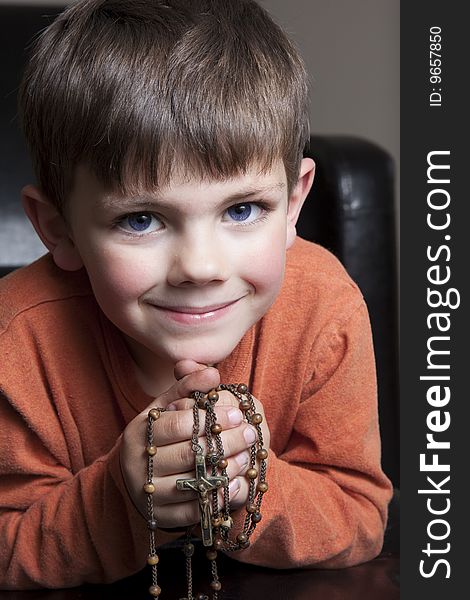 Young boy hold rosery and smiling. Young boy hold rosery and smiling