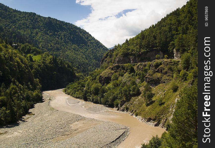 Big valley in Caucasus, Georgia. River blue sky and green forest.