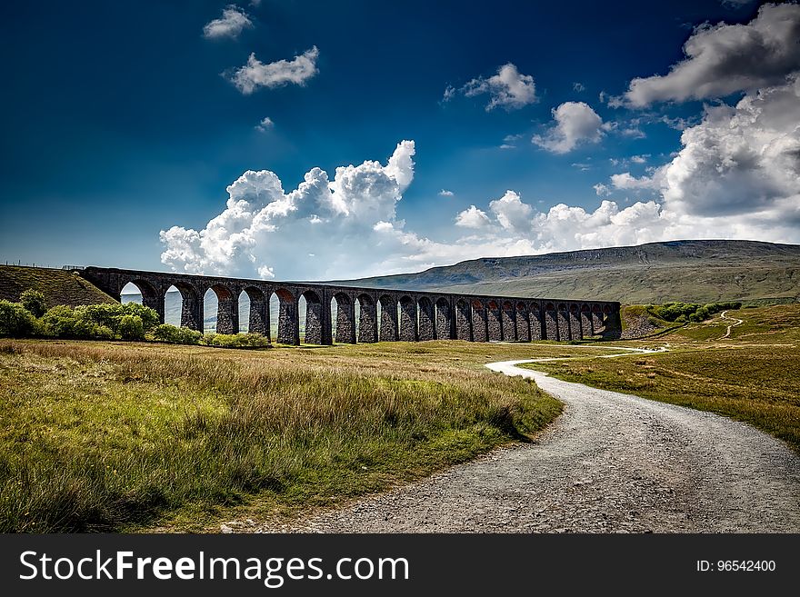 Brown Bridge On Green Grass Field Near Mountain