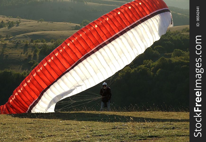 Man on the Ground With a Red Black and White Parachute