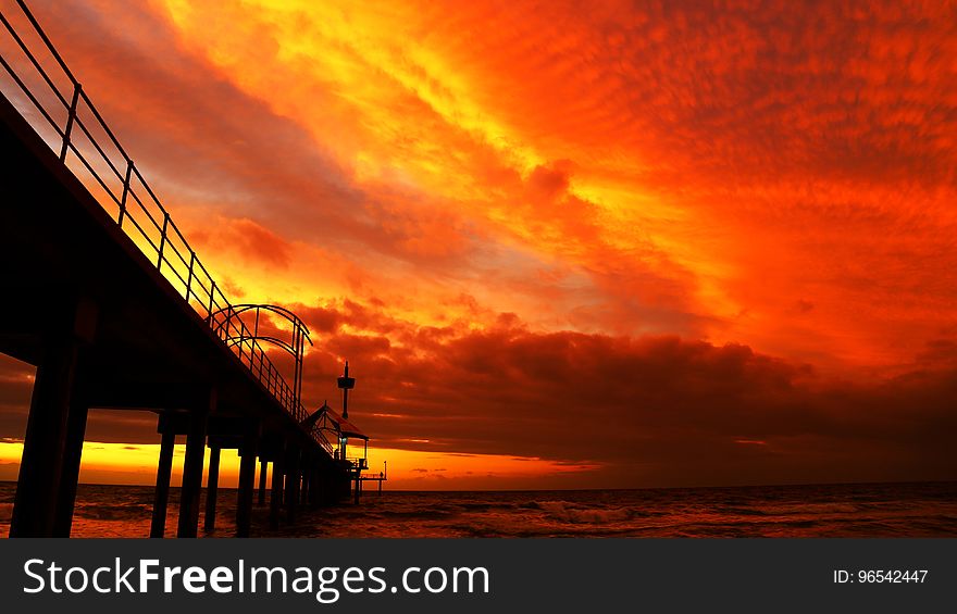 Black Bridge Under Orange Sky during Sunset