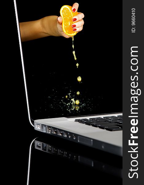 Woman hand squeezing an orange in laptop. Isolated image on a black background with clipping path. Woman hand squeezing an orange in laptop. Isolated image on a black background with clipping path.