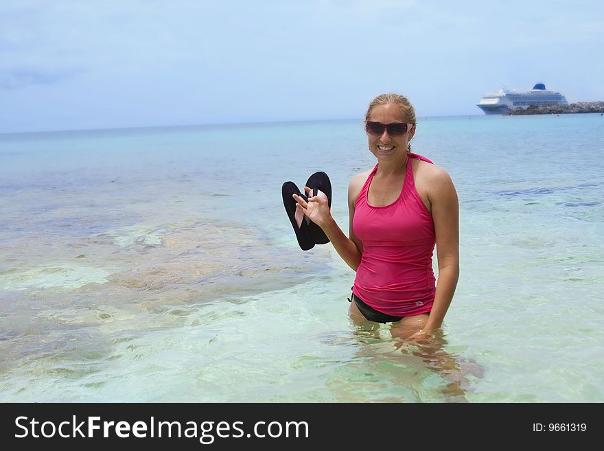 A woman enjoys her Caribbean Cruise vacation. Cruise ship is seen in the background