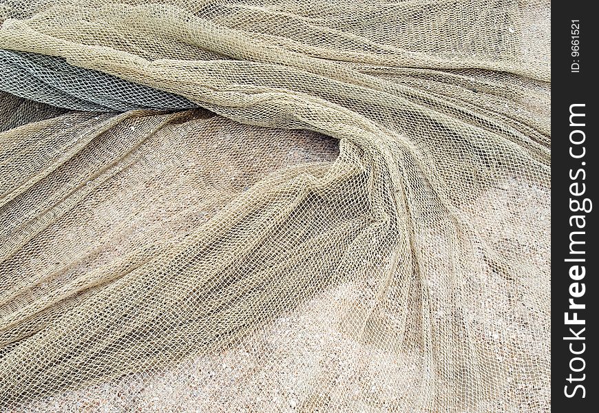 Used fishing net on a sand background. Used fishing net on a sand background.