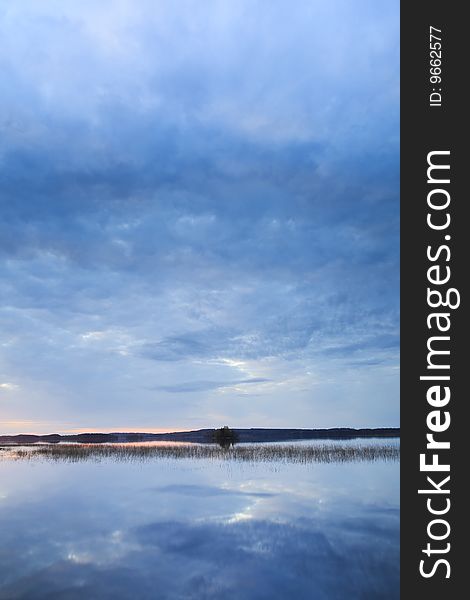 Sunset at calm lake with blue clouds from Finland. Sunset at calm lake with blue clouds from Finland