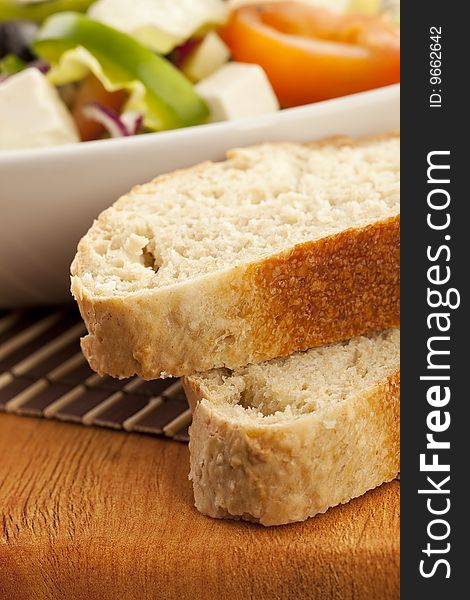 White bread with salad bowl on background on wooden table. White bread with salad bowl on background on wooden table
