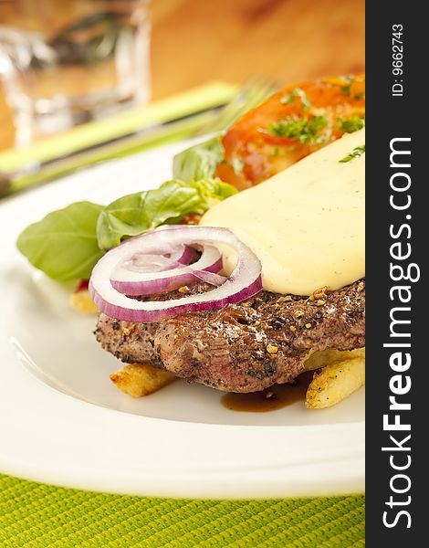 Steak and fries on the plate at restaurant with onion rings, tomatoes, and garnish. Steak and fries on the plate at restaurant with onion rings, tomatoes, and garnish.