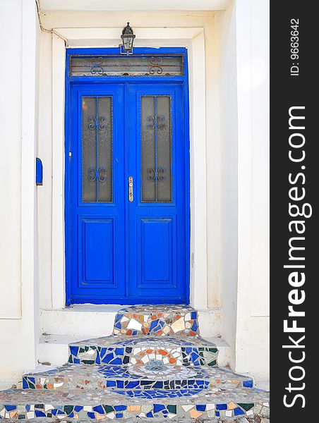 Blue entrance door white wall mosaic decoration. Blue entrance door white wall mosaic decoration