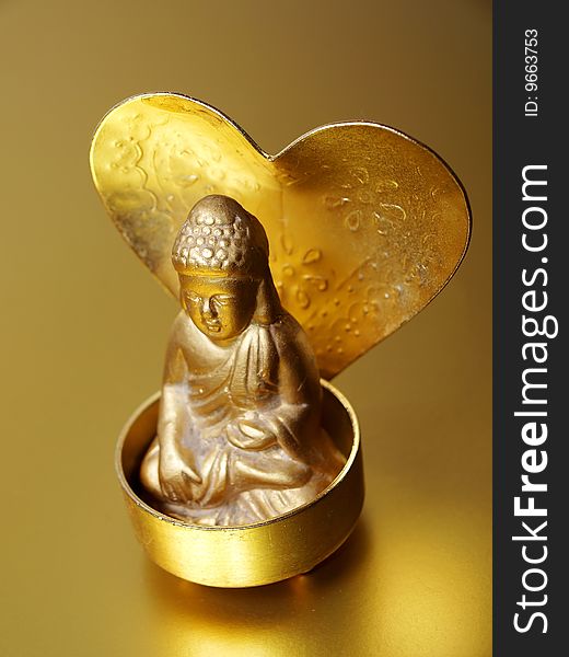 A Buddha is placed in a candle holder with heart shaped golden plate in the back illustration of piece on a golden background. A Buddha is placed in a candle holder with heart shaped golden plate in the back illustration of piece on a golden background