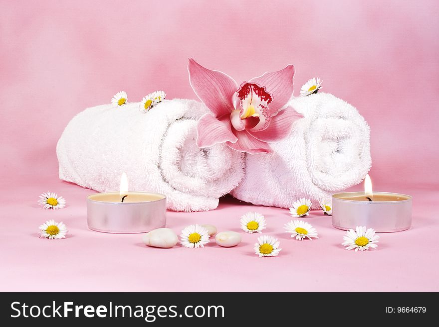 Two towels with a pink orchid and two candels. Two towels with a pink orchid and two candels