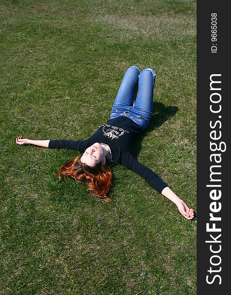 The girl lying on the grass exposing her face to the sun. The girl lying on the grass exposing her face to the sun