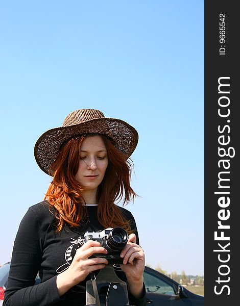 The girl in the hat on  the bank of the lake with camera. The girl in the hat on  the bank of the lake with camera