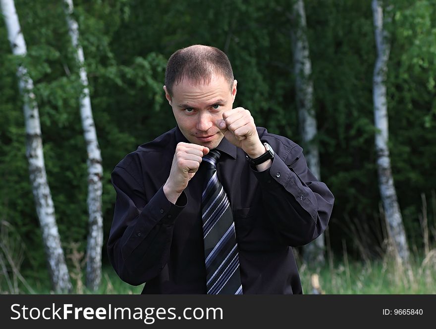 A businessman boxes on nature.