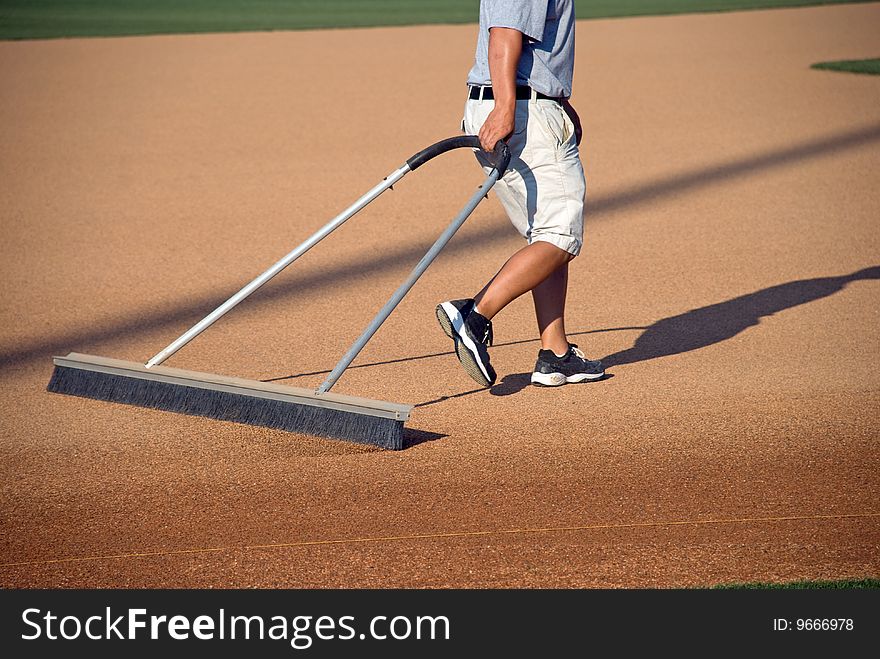 A young man prepares a baseball field for the game. A young man prepares a baseball field for the game.