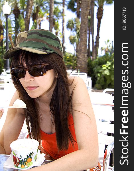 Woman with military hat and sun glasses eating ice cream. Woman with military hat and sun glasses eating ice cream