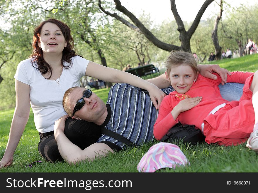 Happy family poses on green lawn in park