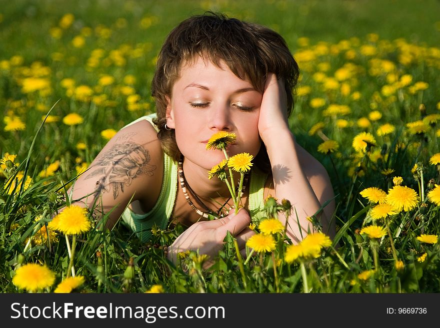 A young cheerful woman having fun on a dandelions glade