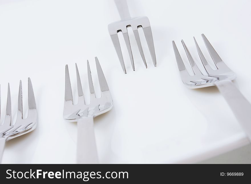 Forks on a white plate. Close-up.