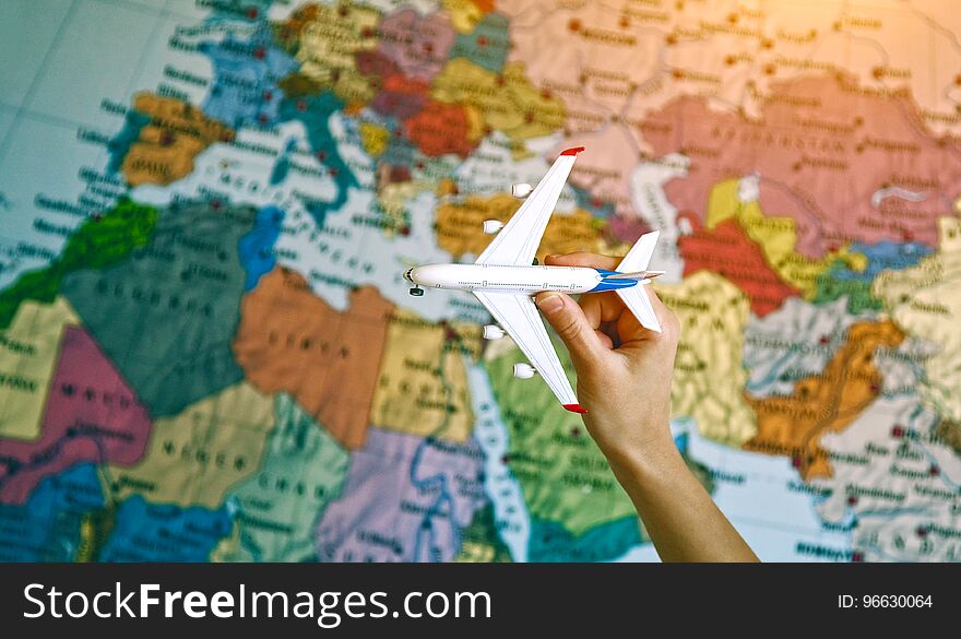 Hand with toy model of airplane on world map background. Hand with toy model of airplane on world map background