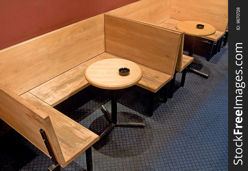 Plunk bench and round wooden tables with ashtray in cafe. Plunk bench and round wooden tables with ashtray in cafe