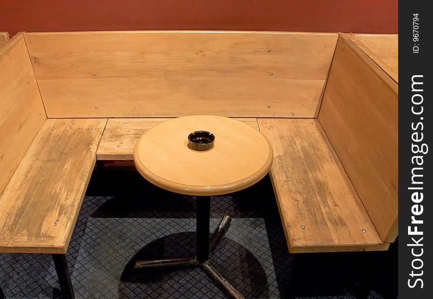 Plunk bench and round wooden table with ashtray in cafe. Plunk bench and round wooden table with ashtray in cafe