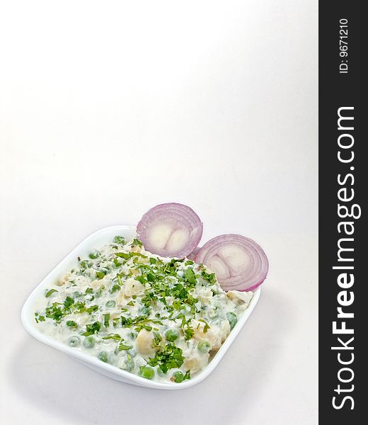 Deliciously cooked baked vegetable placed in a white bowl and garnished with onions. Deliciously cooked baked vegetable placed in a white bowl and garnished with onions