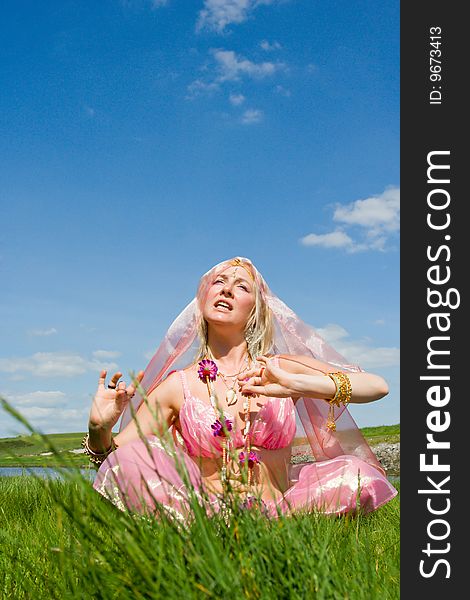 A woman in pink asian dress singing on the ocean shore