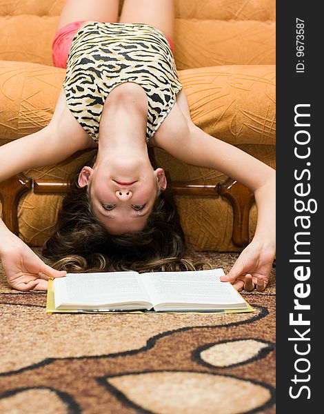 Teen girl reading book on sofa