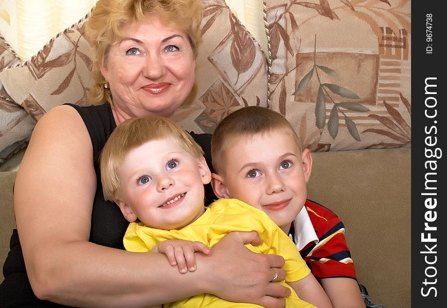 Young grandmother with two grandchildren at home on the couch. Young grandmother with two grandchildren at home on the couch