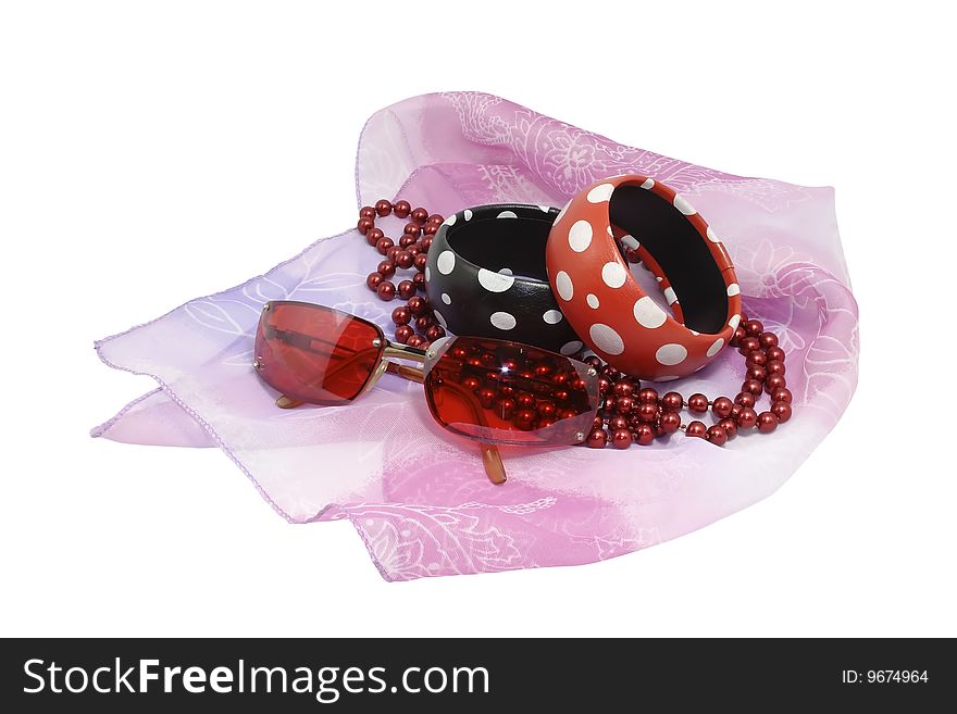 Female costume jewellery and the sun glasses laying on a gentle, pink scarf, represented on the isolated white background. Female costume jewellery and the sun glasses laying on a gentle, pink scarf, represented on the isolated white background