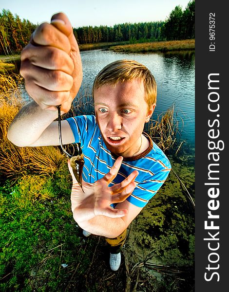 A cute guy showing off a crucian he has just caught. A cute guy showing off a crucian he has just caught