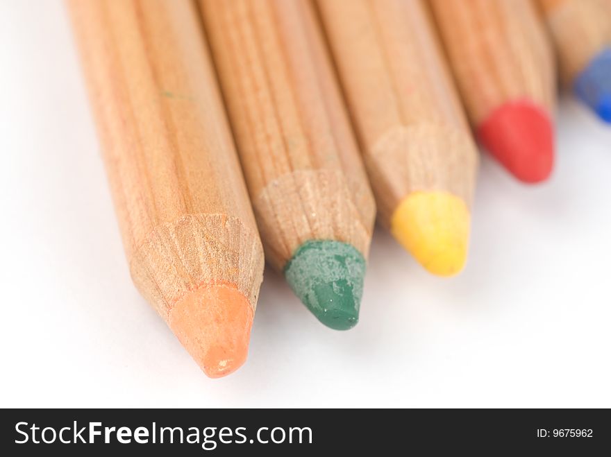 Colored wooden pencils on white background with shadows. Soft focus. Colored wooden pencils on white background with shadows. Soft focus.