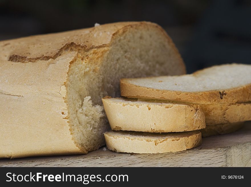 Close up of rustic bread on its chopping board - black background. Close up of rustic bread on its chopping board - black background