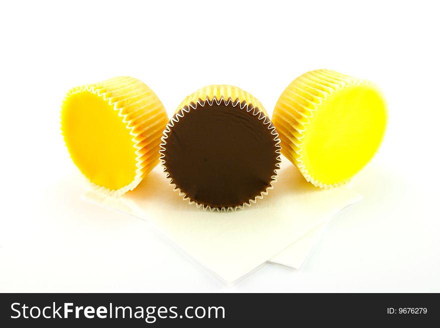 Three delicious looking cup cakes resting on two white napkins on a plain background. Three delicious looking cup cakes resting on two white napkins on a plain background