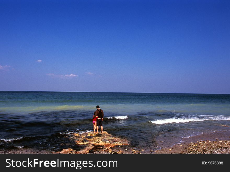 Father and daughter admiring waves and blue sky