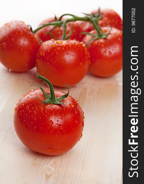 Red fresh group of tomatoes lay on wooden table isolated in studio