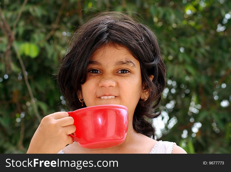 A nice Indian girl making a mischievous face having her morning health drink. A nice Indian girl making a mischievous face having her morning health drink.
