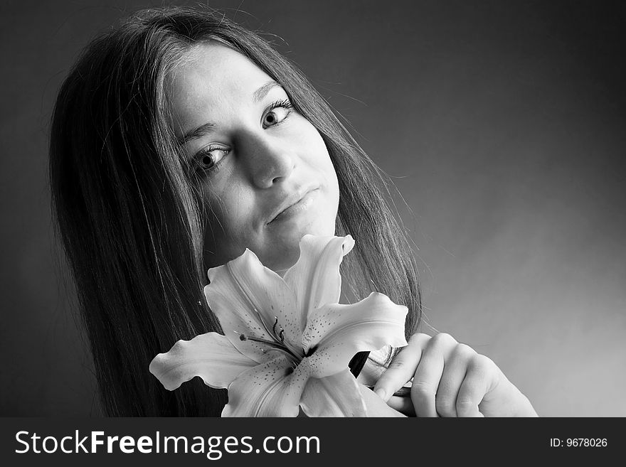 A pretty young woman with long hair posing with a lily in her hand. A pretty young woman with long hair posing with a lily in her hand