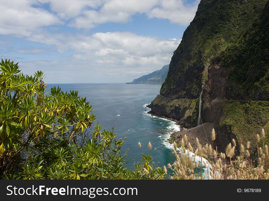 A picture of a mountain coast view with a waterfall coming out of the mountain. This picture is taken in Madeira Portugal. A picture of a mountain coast view with a waterfall coming out of the mountain. This picture is taken in Madeira Portugal