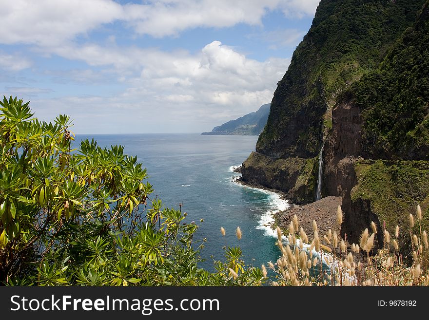 A picture of a mountain coast view with a waterfall coming out of the mountain. This picture is taken in Madeira Portugal. A picture of a mountain coast view with a waterfall coming out of the mountain. This picture is taken in Madeira Portugal