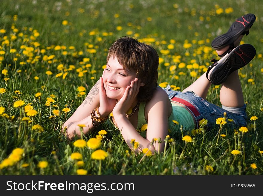 A young cheerful woman having fun on a dandelions glade