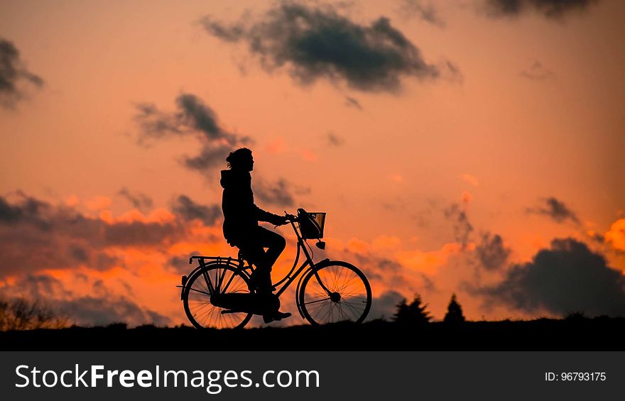 Silhouette of Person Riding a Bike during Sunset