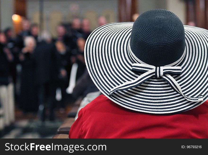 Woman in Red Shirt and Black and White Stripes Sunhat Surrounded by People