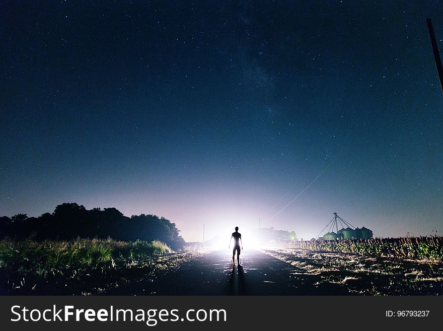 Man Standing on the Road Near Green Grass during Sunrise
