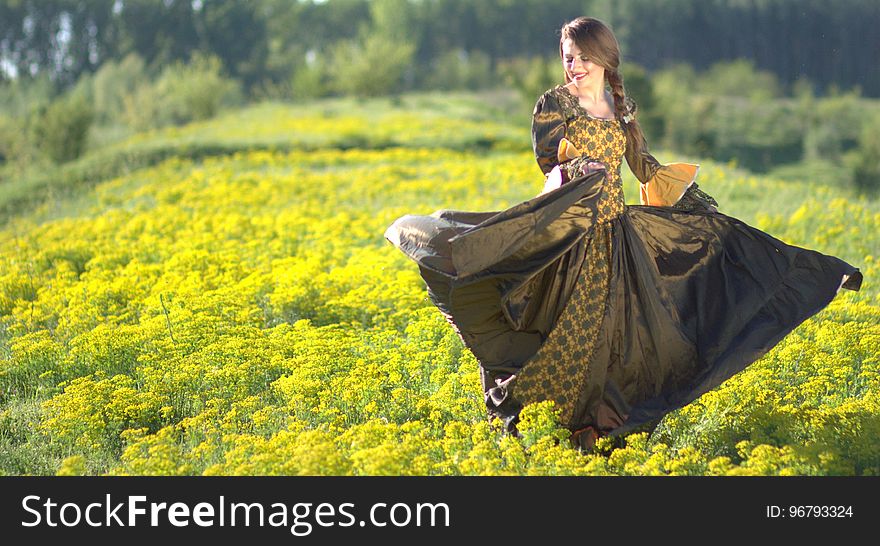 Woman Wearing Black and Brown Dress Standing on Green Grass during Daytime