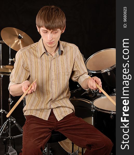 Young musician playing drums on black. Young musician playing drums on black.
