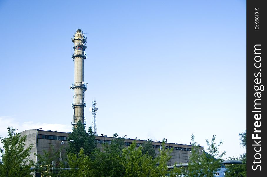 Generic view of a factory with a tall chimney and clear blue sky.