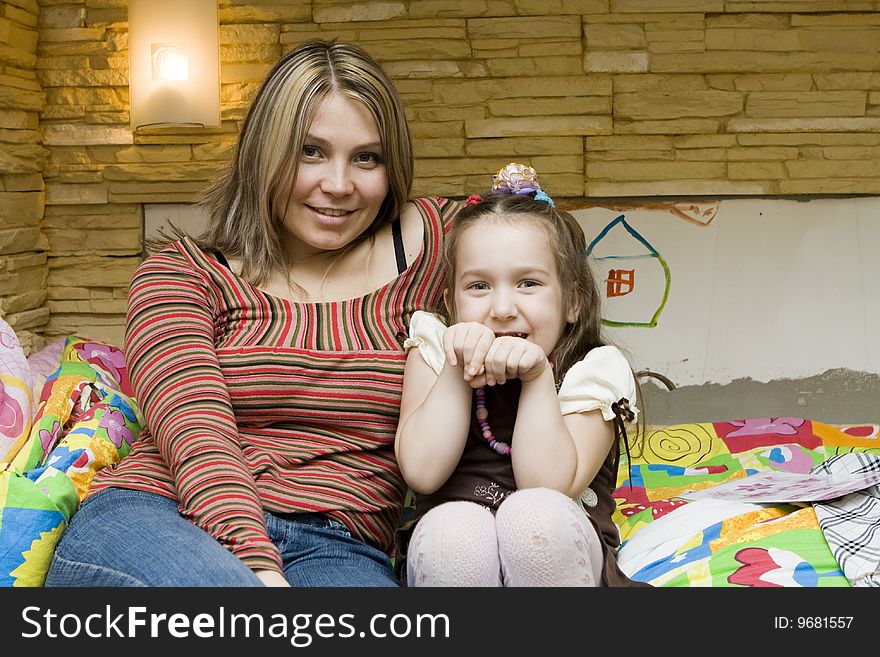 Cute girl sitting with beautiful mother at home