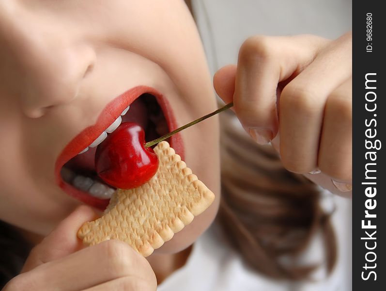 Young girl opened mouth eating red cherry and cake. Young girl opened mouth eating red cherry and cake